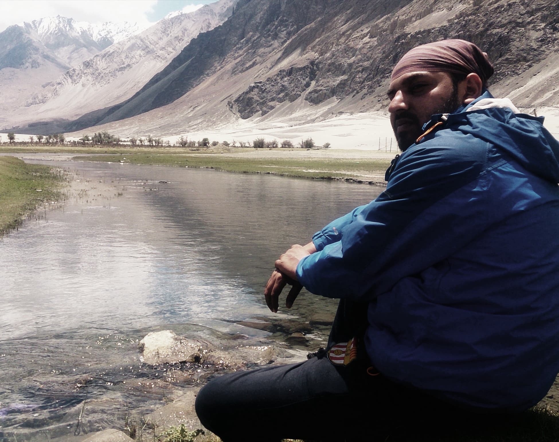 Deepak sitting beside a river in a mountain valley